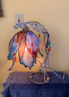 a lamp that is sitting on top of a blue table cloth with beads hanging from it