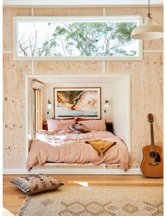 a bedroom with wood paneling and a guitar on the floor in front of it