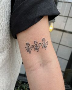 a woman's arm with three small flowers on the left side of her arm