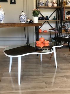 a table with pumpkins on it in front of a shelf filled with vases