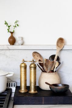 brass kitchen utensils and spoons are sitting on a counter top next to a stove