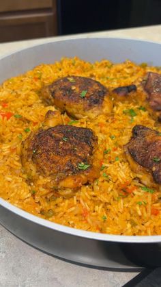 a pan filled with rice and meat on top of a counter next to a knife