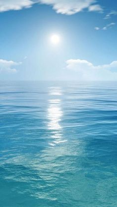 the sun is shining over the ocean with clear blue water and white clouds in the sky