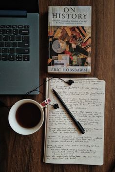 a notebook, pen and cup of coffee on a table