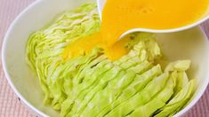 a bowl filled with lettuce and dressing being drizzled over it