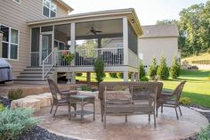 a patio with chairs and tables in front of a house that has a covered porch