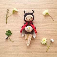 a crocheted doll sitting on top of a wooden table next to white flowers