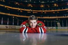 a hockey player laying on the ice in front of an empty arena looking at the camera