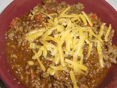 a red bowl filled with chili and cheese