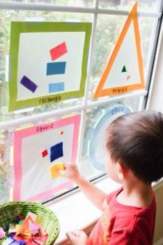 a little boy that is sitting in front of a window with some papers on it