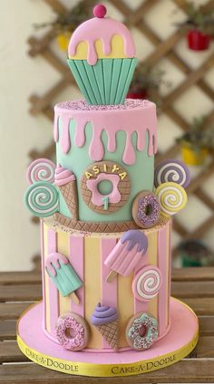 a three tiered cake decorated with donuts and icing on a wooden table