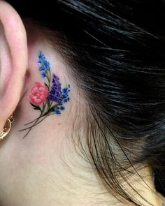 a close up of a person's ear with flowers behind her ear and behind the ear tattoo