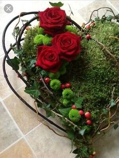 a heart shaped arrangement with red roses and green moss