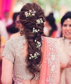 a woman in a bridal gown with flowers in her hair and another woman standing behind her