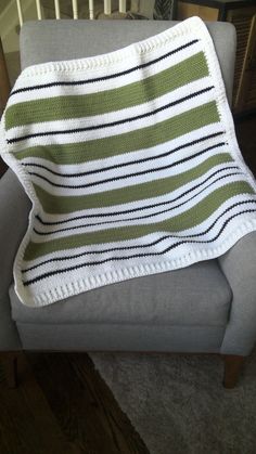 a green and white striped blanket sitting on top of a gray couch next to a chair