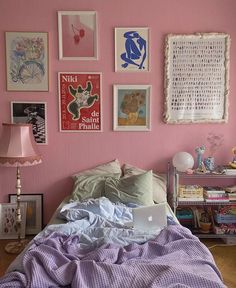 a bedroom with pink walls and lots of pictures on the wall above the headboard