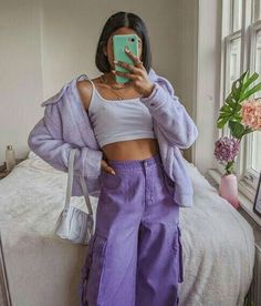 a woman taking a selfie while wearing purple pants and a white cropped top