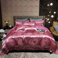 a bed with pink comforter and pillows in a hotel room, next to a chair