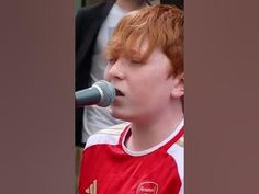 a young boy with red hair singing into a microphone