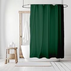 a green shower curtain hanging over a bathtub in a white bathroom with wooden flooring