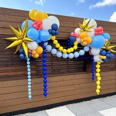 balloons and streamers are hanging from the side of a building with stars on them