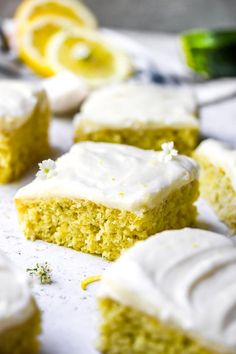 several pieces of cake with white frosting and lemon zest on top, sitting on a sheet of parchment paper