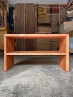 a wooden bench sitting on top of a cement floor in a room filled with boxes