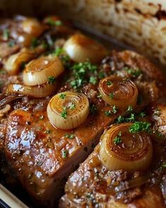 meat with onions and garlic on top in a casserole dish, ready to be eaten