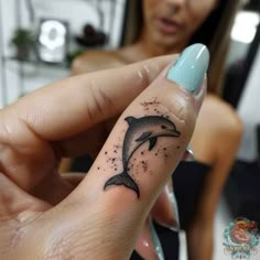 a woman with a dolphin tattoo on her finger