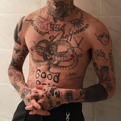 a man with many tattoos on his chest and arms is standing in front of a tiled wall