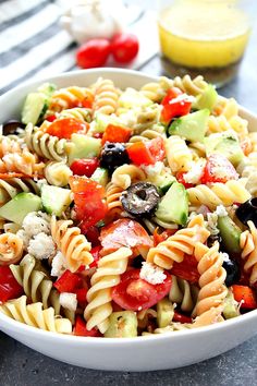 a pasta salad with tomatoes, cucumbers and olives