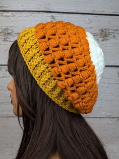 a woman wearing a yellow and white crocheted beanie with an orange stripe