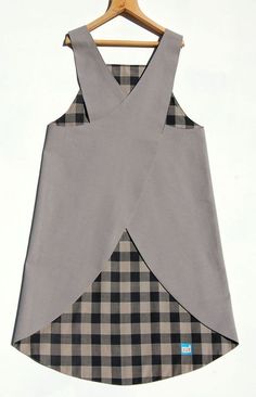 a dress hanging on a wooden hanger with a checkered pattern and grey fabric