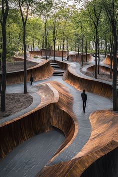 a man walking down a wooden ramp in a park with many trees on both sides