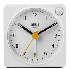 a white square clock with yellow hands and numbers on the face is shown against a white background