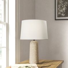 a table lamp sitting on top of a wooden table next to a book and cup