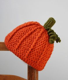 an orange knitted hat sitting on top of a wooden chair