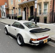 an old white porsche parked on the side of the road in front of some buildings