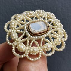 A beautiful mourning brooch, made of many seed pearls which have been finely entwined using clear wire, and are backed with a carved mother of pearl plaque. In the centre is a glass locket compartment, which houses a small lock of hair. The reverse shows a small portrait of a gentleman. With a gold pin and 'C' catch fitting.Circa late Georgian - early Victorian era.Unmarked, fittings tested as gold.The brooch measures approximately 39.2mm x 34.8mm.The glass locket compartment measures approximat Heirloom Cameo Brooch For Wedding, Heirloom Cameo Brooches For Weddings, Heirloom Cameo Wedding Brooch, Victorian Style Cameo Brooch For Weddings, Victorian Cameo Brooch For Wedding, Antique Medallion Brooch For Wedding, Antique Wedding Brooch With Intricate Design, White Cameo Brooch For Wedding, Vintage Medallion Brooch For Wedding