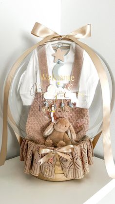 a teddy bear sitting in a basket under a glass dome on top of a shelf