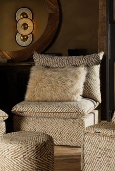 an upholstered chair and foot stool in front of a mirror with a clock on the wall