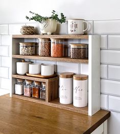 the shelves are filled with spices and jars on top of each other in front of a white brick wall