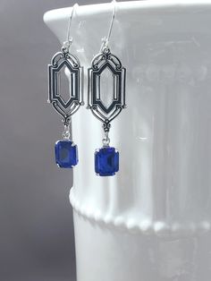 These Deco dangles are the perfect earrings for a 1920s themed wedding or party.  Sapphire blue vintage glass beads dangle from antiqued silver-plated brass Art Deco style connectors. The blue color is a medium blue. The silver-plated brass stamping connectors have an ornate front and a reverse side that is slightly hollow. (SEE 2nd PHOTO) These earrings are lightweight yet sturdy, lobe-friendly, and free of lead and nickel. The earrings measure 2 1/4 inches long from the top of the ear wires to the bottom of the glass beads. They hang from silver plated lever back ear wires. A versatile classic design that can be worn for weddings or work.  ABOUT THIS COLLECTION The sophisticated style of the Roaring Twenties is timeless. The sparkling crystal and luminous pearl jewels in this collection Art Deco Dangle Earrings For Vintage Events, Art Deco Earrings For Vintage Events, Elegant Nickel-free Chandelier Earrings For Evening, Blue Art Deco Jewelry For Party, Handmade Elegant Earrings For Vintage Style, Vintage Sterling Silver Earrings For Parties, Victorian Style Nickel Free Earrings For Party, Victorian Dangle Chandelier Earrings For Parties, Victorian Chandelier Dangle Earrings For Party