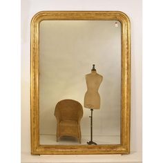 a mannequin is in front of a gold framed mirror