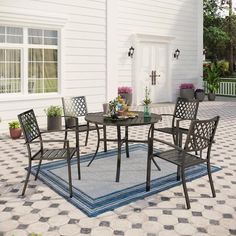 a patio table with four chairs and a rug on the ground