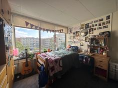 a bedroom with a guitar on the bed and lots of pictures on the wall behind it