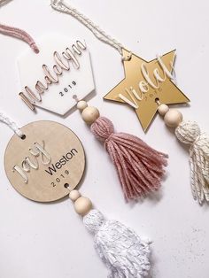 wooden name tags with tassels and tassels hanging from strings on a white surface