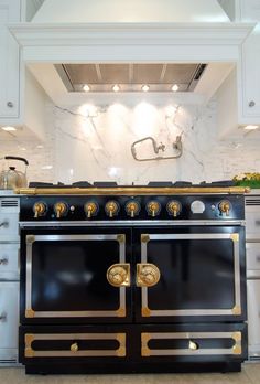 a black and gold stove top oven in a white kitchen with marble counter tops on both sides