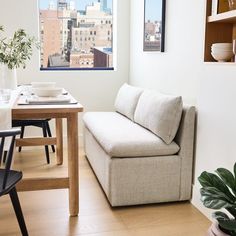 a couch sitting in front of a window next to a table with plates on it