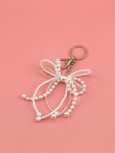 a keychain with pearls on it and a bow hanging from the front, against a pink background